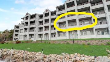 A multi-story hotel with a symmetrical facade, balconies on each floor, and a stone retaining wall in the foreground.