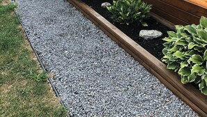 A garden with raised beds, a wooden deck, and a red umbrella. - Oak Street Cottage - 3BRM with Backyard Retreat (Prince Edward)