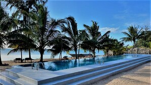 Ein Pool mit Stufen, umgeben von Palmen und einem Strand.