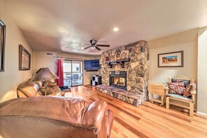 A living room with a stone fireplace, leather sofa, and wooden flooring.