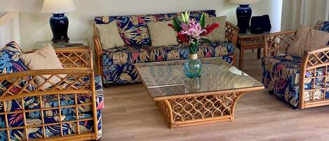 A living room with a sofa, two armchairs, a glass coffee table, and two lamps.