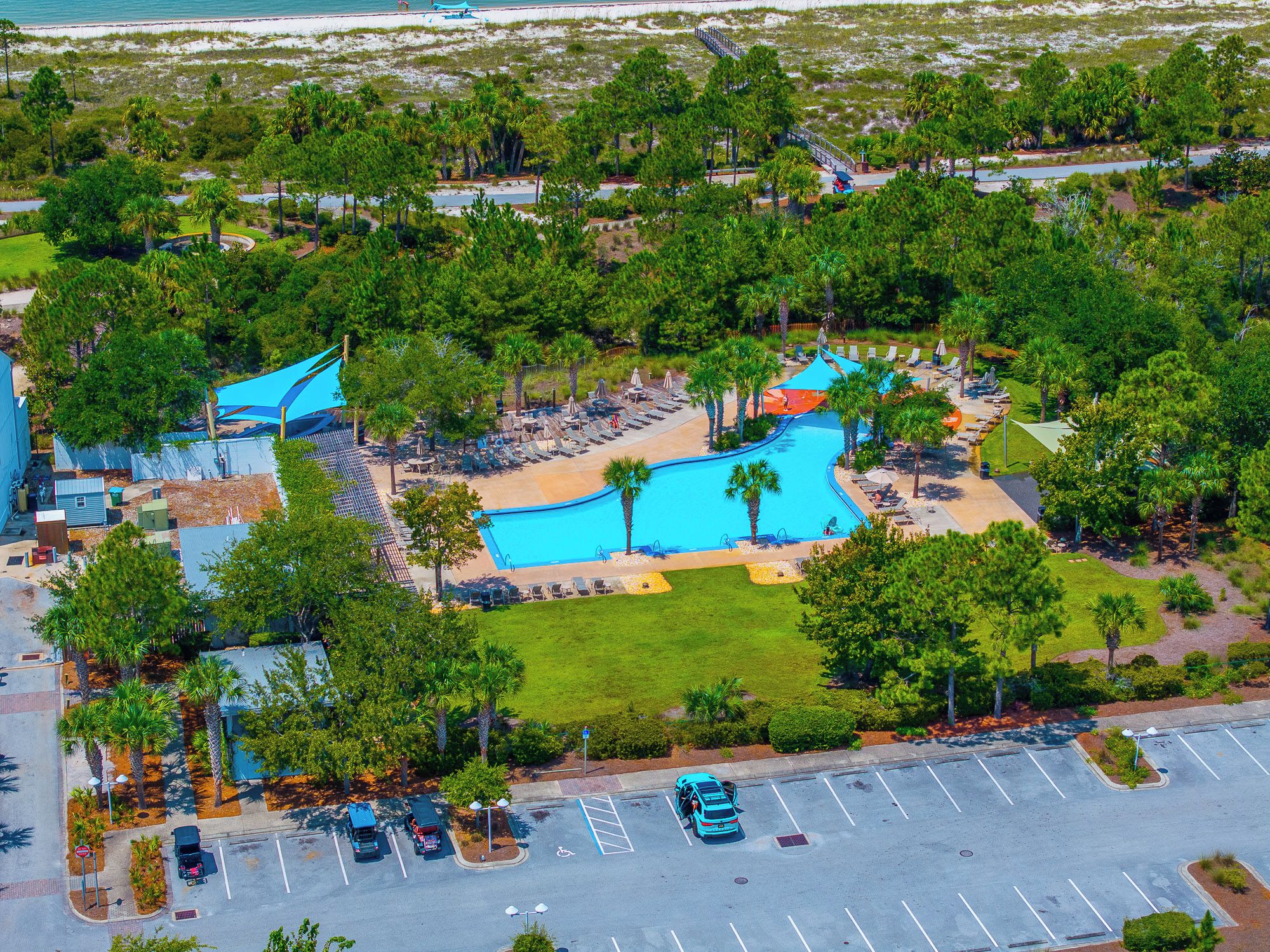 A resort with a swimming pool, lounge areas, and a parking lot.