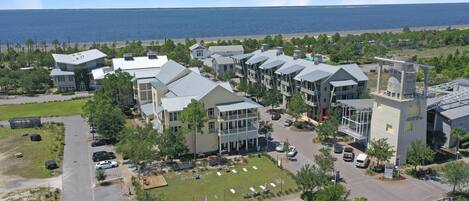 A coastal hotel with multiple buildings, a parking lot, and a view of the ocean.