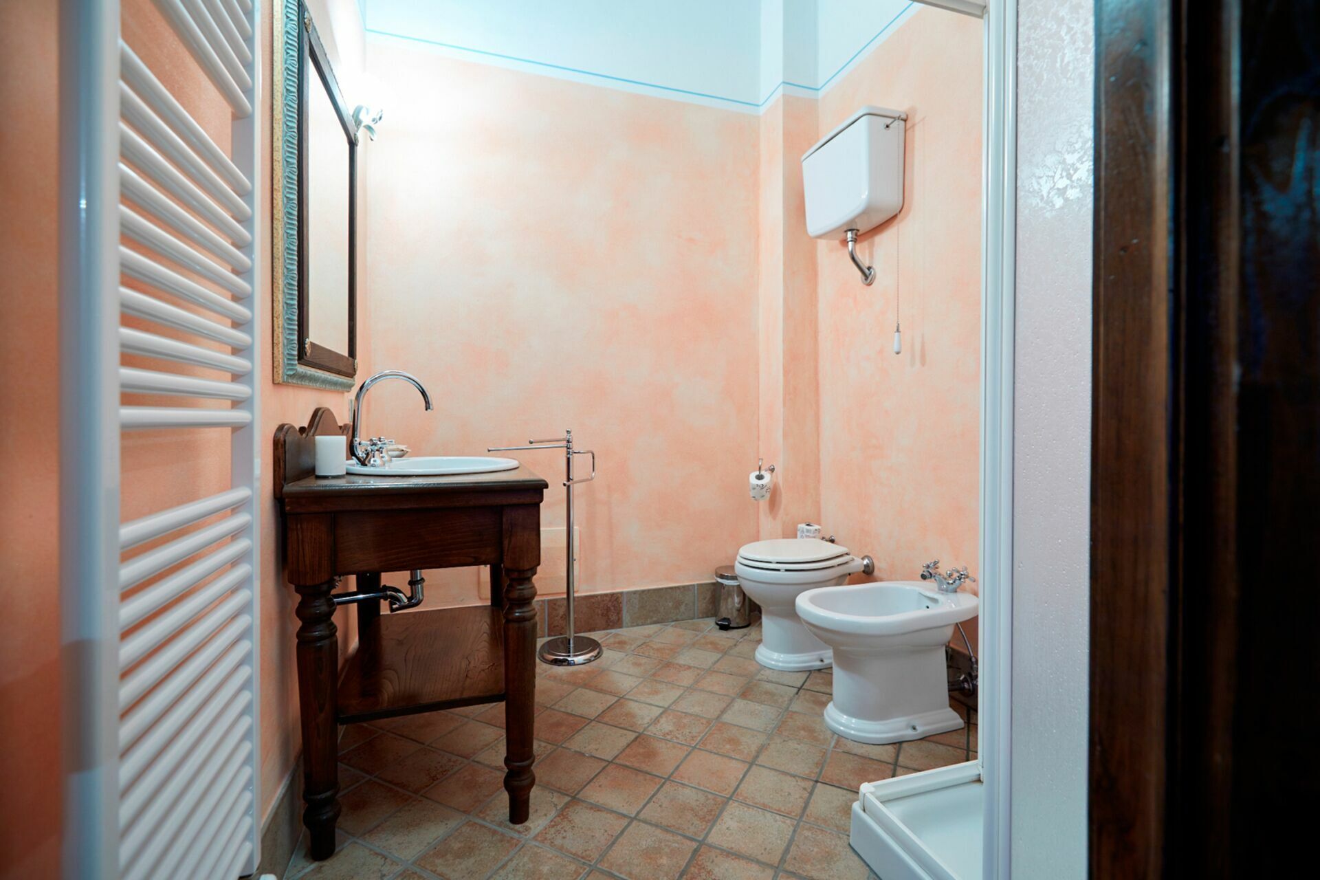 Une salle de bain avec un meuble-lavabo en bois, un lavabo, des toilettes et un bidet.