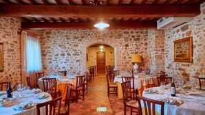 Um restaurante com paredes de pedra, vigas de madeira e mesas preparadas para refeições.