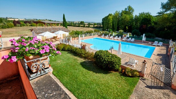 A swimming pool with lounge chairs and umbrellas, surrounded by a well-maintained lawn and a view of the countryside. - Nice apartment for 2 guests with pool, WIFI, TV and balcony, close to Spoleto (Uncinano)
