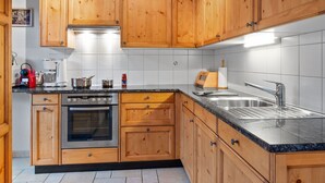 A kitchen with wooden cabinets, a stainless steel sink, and a built-in oven. - Beautiful apartment for 4 people with WIFI, TV, balcony and pets allowed (Les Crosets)