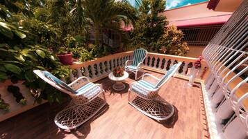 A balcony with wicker furniture, a small round table, and potted plants.