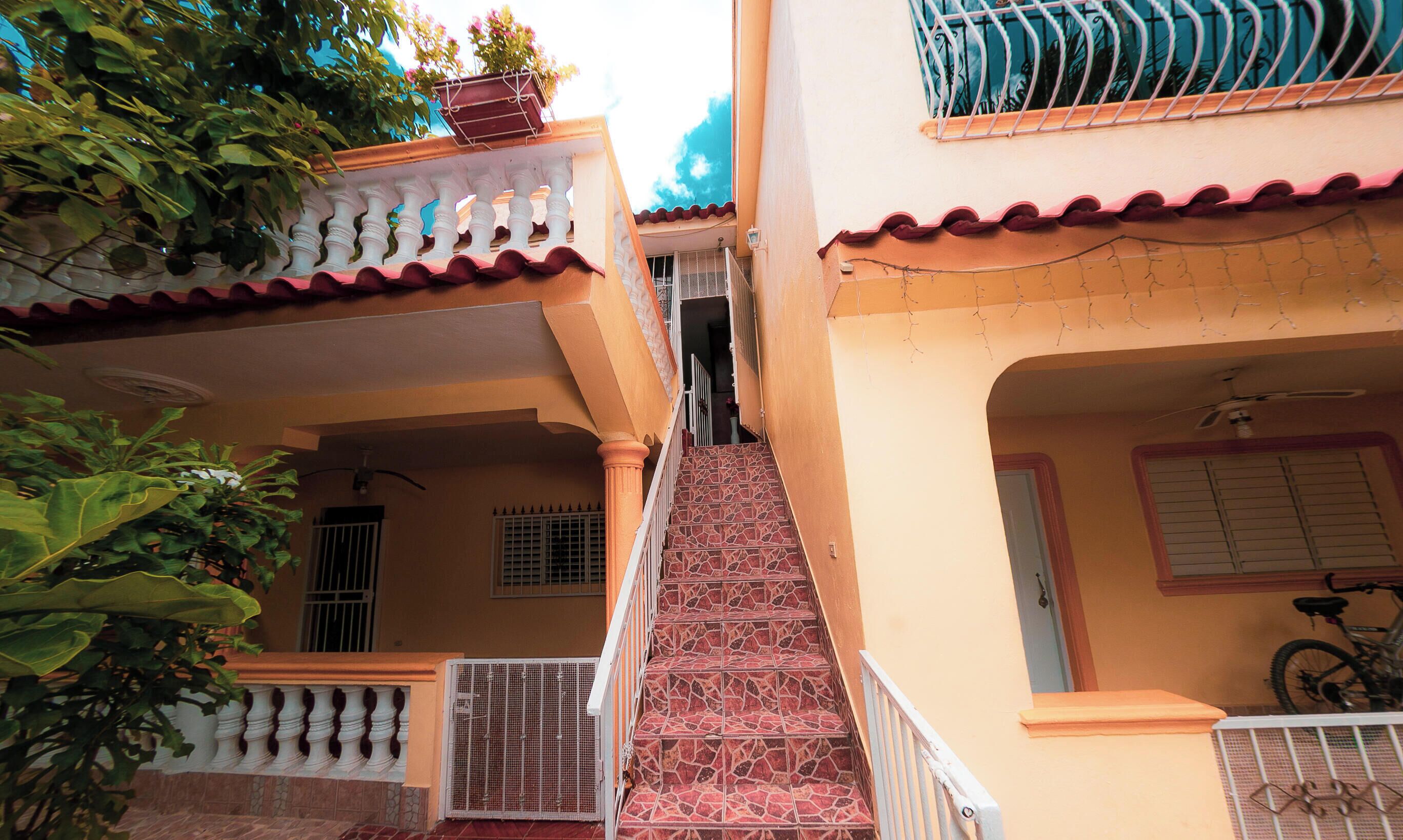 A staircase leading to a balcony with a railing, a bicycle parked inside, and a gate at the bottom.