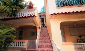 A staircase leading to a balcony with a railing, a bicycle parked inside, and a gate at the bottom.