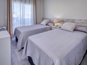 Two single beds with matching bedding and a bedside table with a lamp.