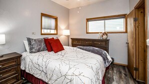 Une chambre à coucher comprenant un lit, une table de chevet, une commode, une lampe et un ventilateur de plafond.