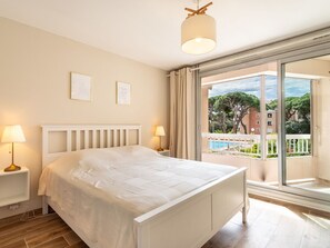 Relax in this serene bedroom with a large bed, bedside tables, and a sliding door leading to a balcony with a pool view.
