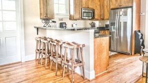 Una cocina con armarios de madera, un refrigerador de acero inoxidable y una barra con taburetes.