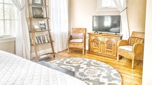 Una sala de estar acogedora con una estantería, un televisor y dos sillones de mimbre.