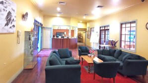A spacious living area with a wooden floor, a reception desk, and a seating area with sofas and a coffee table. - Acheron Valley Country Estate (Acheron)