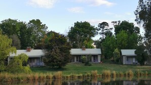A row of cabins with a pond in the foreground, surrounded by trees. - Acheron Valley Country Estate (Acheron)