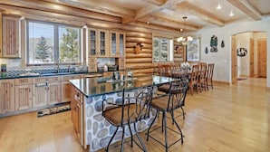 A spacious kitchen with a large island, wooden cabinetry, and a dining area with bar stools. - Home on the 5th Green - Golf, Gameroom, Huge Patio (Angel Fire)
