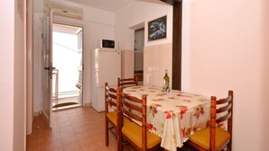A dining area with a table set for four, a refrigerator, and a microwave in the background. - C apt w balcony, shared terrace & the sea view (Arbanija)