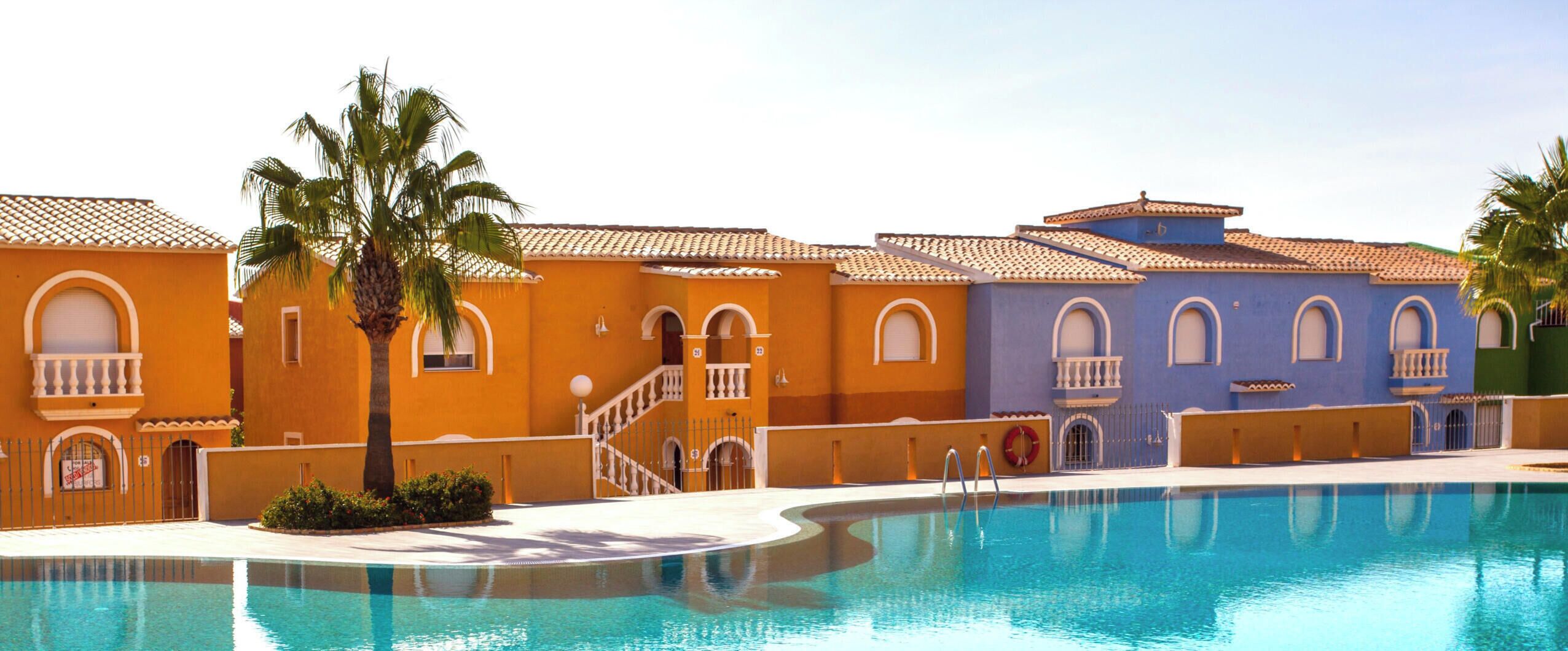 A swimming pool with a curved edge, surrounded by buildings with arched windows and balconies.