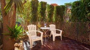 An outdoor seating area with two white chairs and a small round table, surrounded by a wooden fence and lush greenery. - SANDRINE apartment in Benitachell – 2 terraces, swimming pool, air conditioning and Wi-Fi, 1.8 km from Cala Moraig (Benitachell)