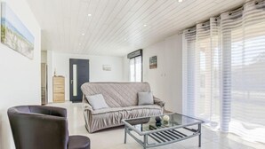 Een moderne woonkamer met een bank, een glazen salontafel en een zwarte fauteuil.
