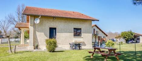 A single-story house with a tiled roof, a satellite dish, a small garden, and a picnic table.