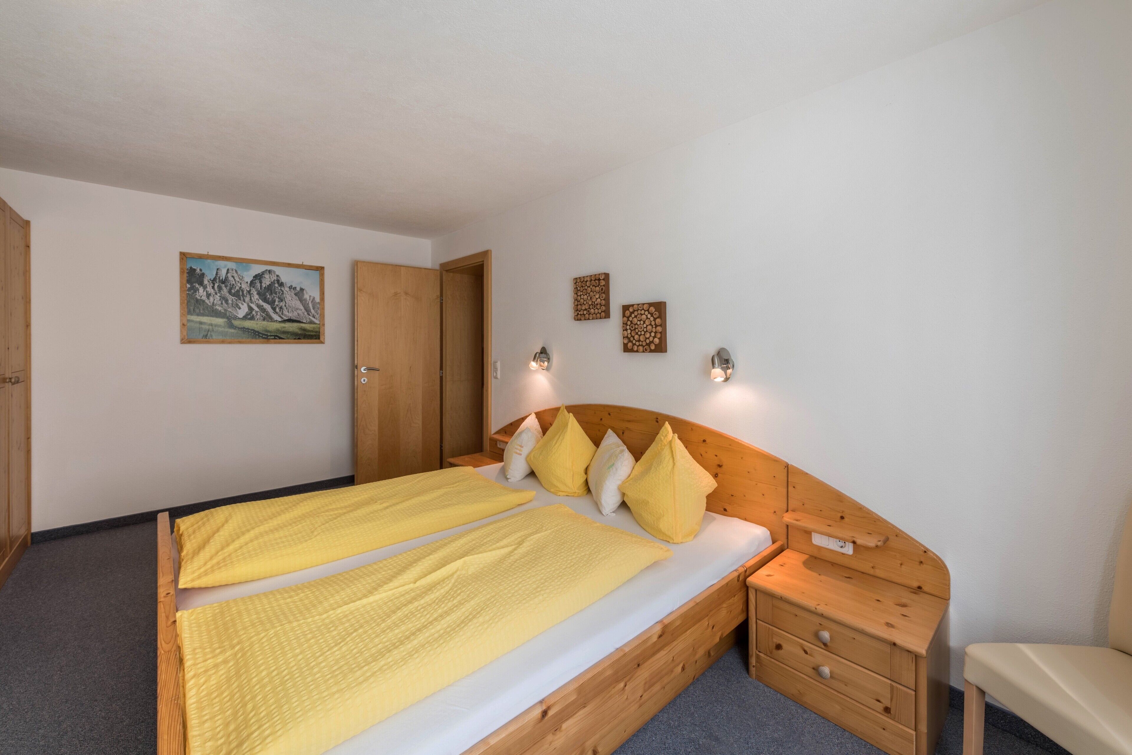 Une chambre à coucher avec un lit en bois, des tables de chevet, un banc et des lampes fixées au mur.