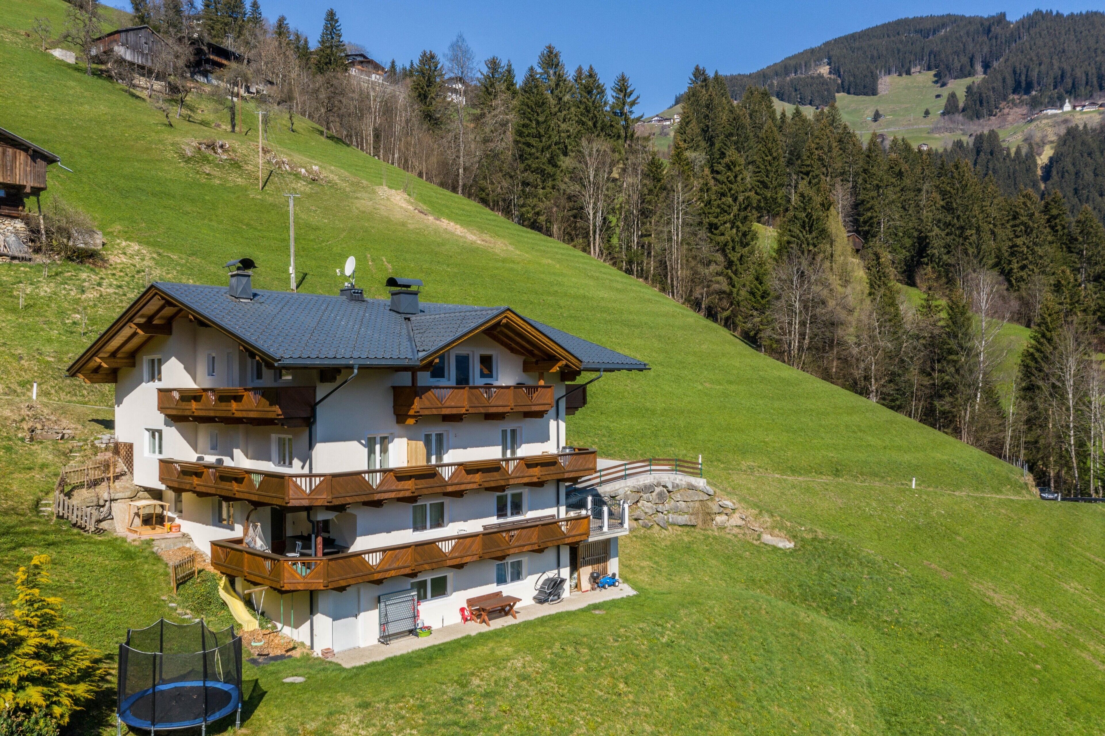 Una chalet a più piani con balconi, un trampolino e una seggiovia sullo sfondo.