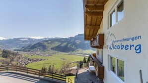 Hotel com varanda e vista para um vale e montanhas.