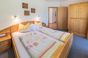 A bedroom with a wooden bed, bedside tables, a wardrobe, and wall-mounted light fixtures.
