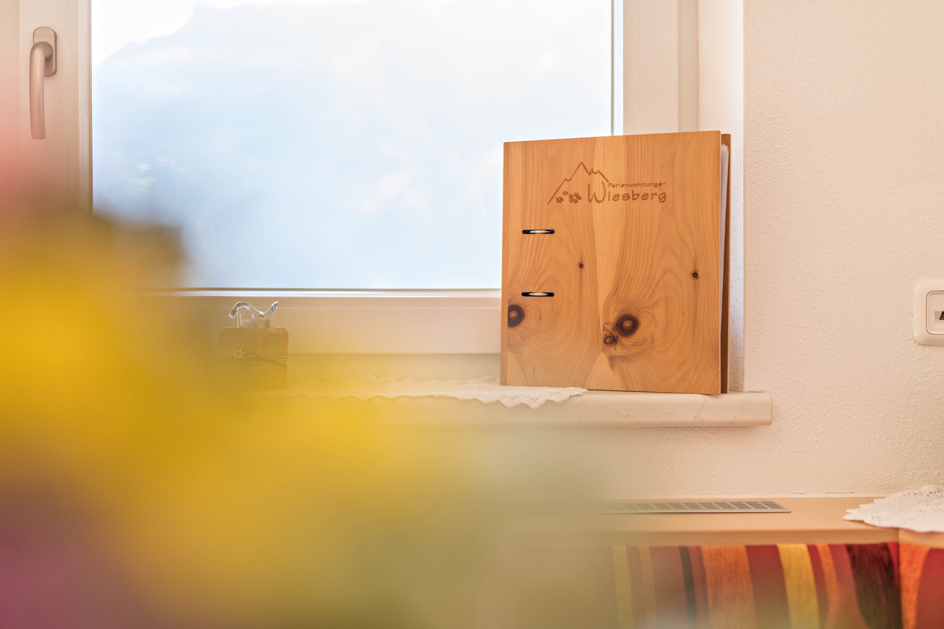 A wooden cabinet with a mountain design and the text 'Wiesberg' on a window sill.