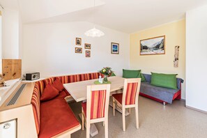 A compact living space with a dining table, chairs, a sofa, and a kitchenette area.