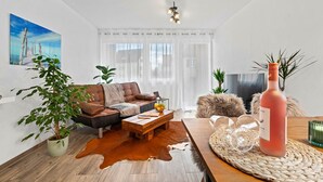 A modern living room with a leather sofa, a coffee table, a potted plant, and a bottle of wine. - Holiday Apartment "Fairschlafen Am See" with Private Terrace & Wi-Fi (Friedrichshafen)