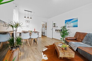 A modern living room with a sofa, a coffee table, and a dining area with chairs.