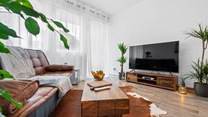 A modern living room with a leather sofa, a wooden coffee table, a flat-screen TV, and a cowhide rug. - Holiday Apartment "Fairschlafen Am See" with Private Terrace & Wi-Fi (Friedrichshafen)