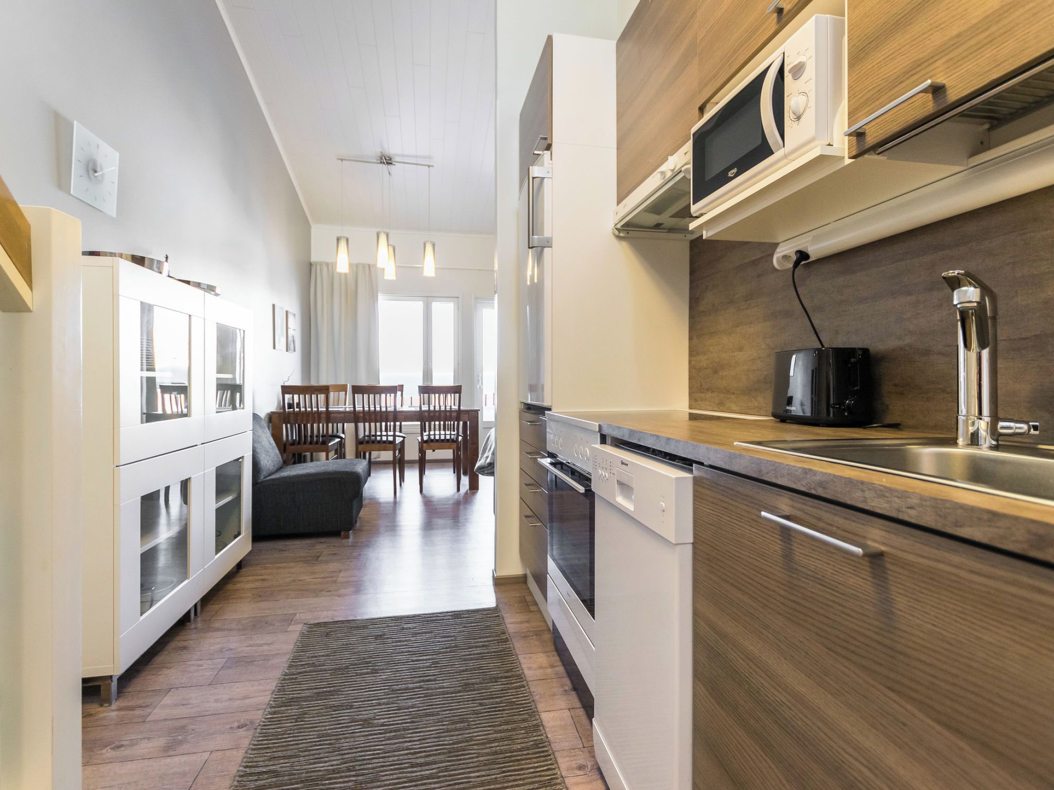 Una cocina moderna con electrodomésticos integrados, una zona de comedor con mesa y sillas de madera, y vistas al comedor.