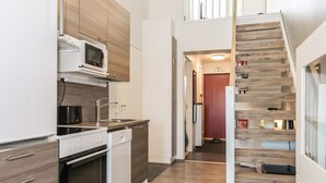A modern kitchen with built-in appliances, a wooden staircase, and a view of the living area. - Skivillas 61 ukkohalla (b8) by Interhome (Hyrynsalmi)