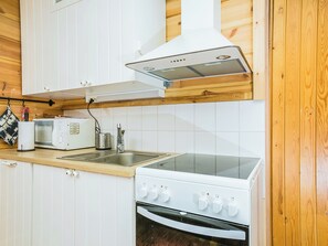 Eine kleine Küche mit weißen Schränken, einer Mikrowelle, einem Toaster, einem Spülbecken und einem Herd.