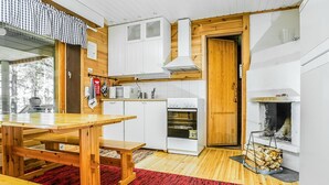 Une cuisine compacte avec des meubles blancs, un four à micro-ondes, un four traditionnel et un poêle à bois.