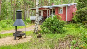 Une cabane dotée d’un porche, entourée d’une forêt.