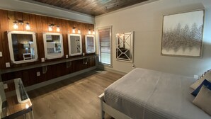 Une chambre avec un plafond en bois, un lit, une table en verre et un mur orné de plusieurs miroirs et d’un tableau.