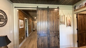 Un couloir aux murs et au sol en bois, une porte coulissante de style grange et des tableaux encadrés accrochés aux murs.