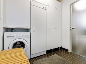 A laundry room with a washing machine, cabinets, and a door. - Skivillas 78 ukkohalla (7) by Interhome (Hyrynsalmi)