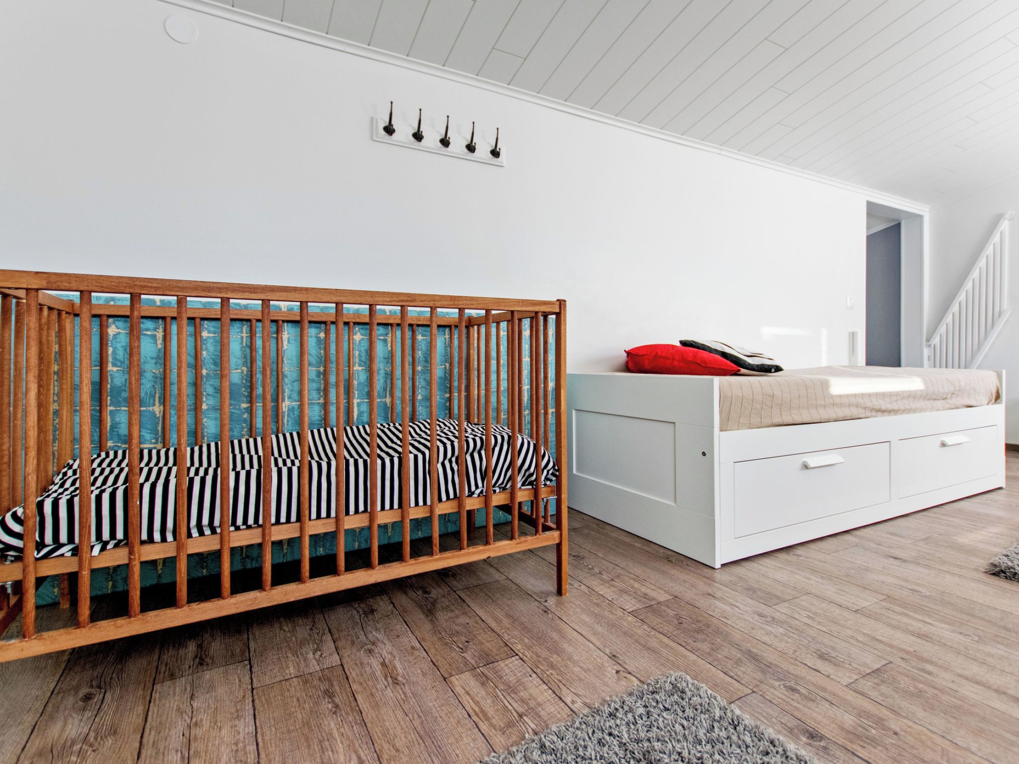 Ein Zimmer mit einem hölzernen Wiege, einer weißen Kommode und einer Treppe.