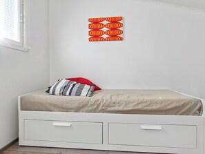 A single-bed room with a plain wall, a window, and a wall decoration. - Skivillas 78 ukkohalla (7) by Interhome (Hyrynsalmi)