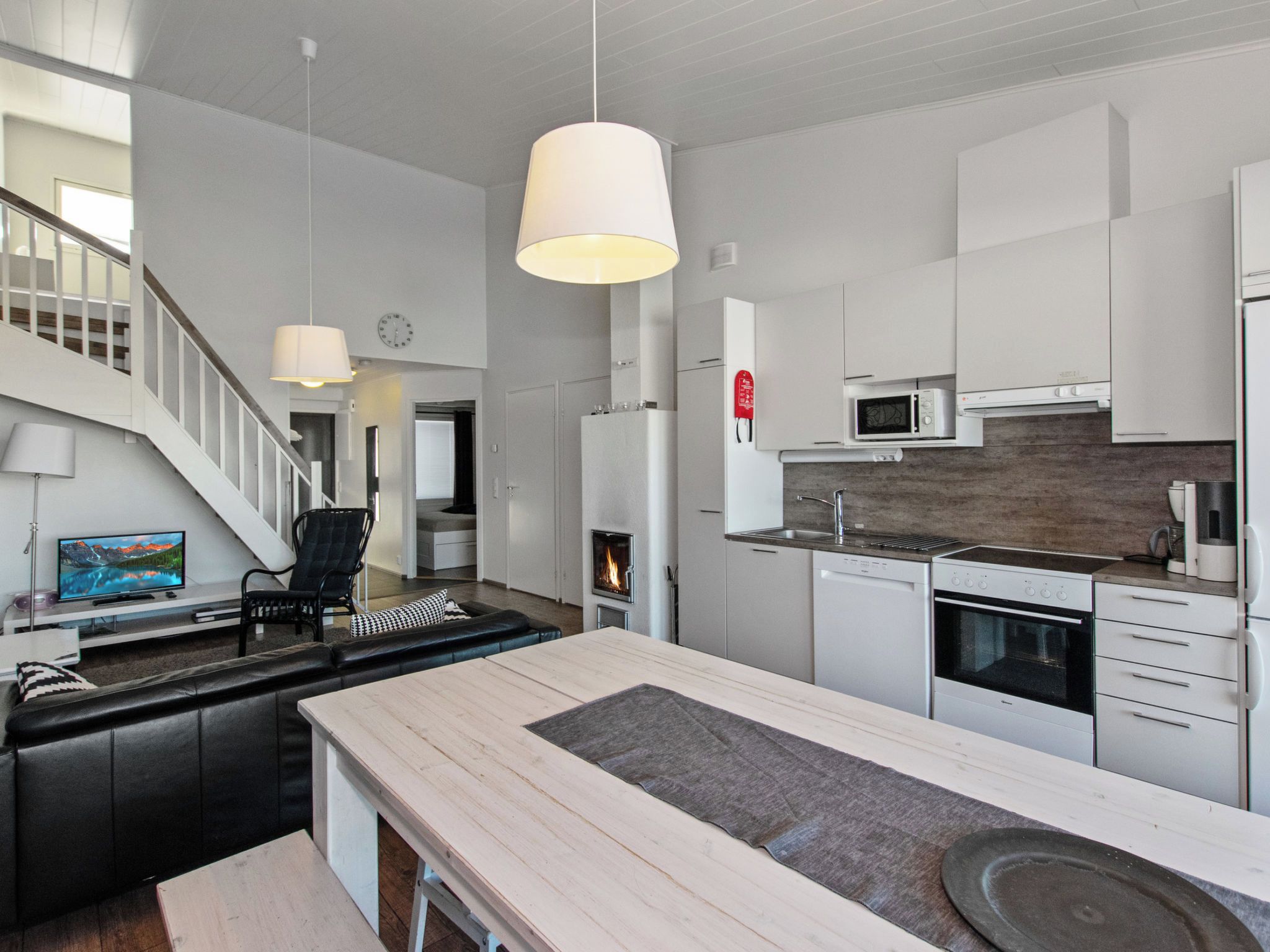 A modern kitchen with white cabinetry, a central island, a built-in stove, and a microwave.