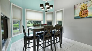 A dining area with a table and chairs, a chandelier, and a painting on the wall. - Cozy Retro Chic Sarasota Home (Sarasota)