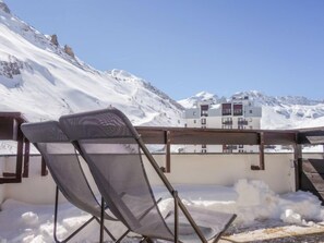 A snow-covered outdoor seating area with a mountain view, a building with balconies, and a clear sky. - Home Club (Lavachet) by Interhome (Tignes)