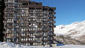 Un hôtel à plusieurs étages, doté de balcons, situé dans une région montagneuse enneigée.